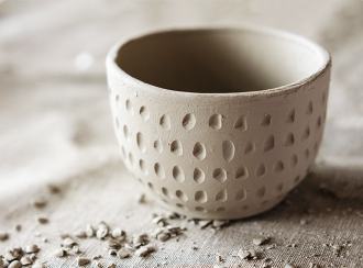 Clay artisian bowl with small dug-out indentations covering the outside surface
